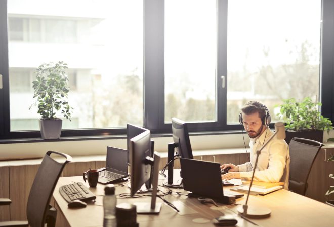 man with headphones facing computer monitor