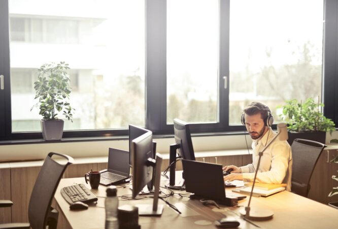man with headphones facing computer monitor