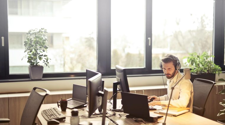 man with headphones facing computer monitor